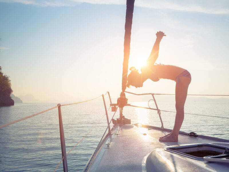 Wellness yacht charter woman doing yoga on bow at sunrise