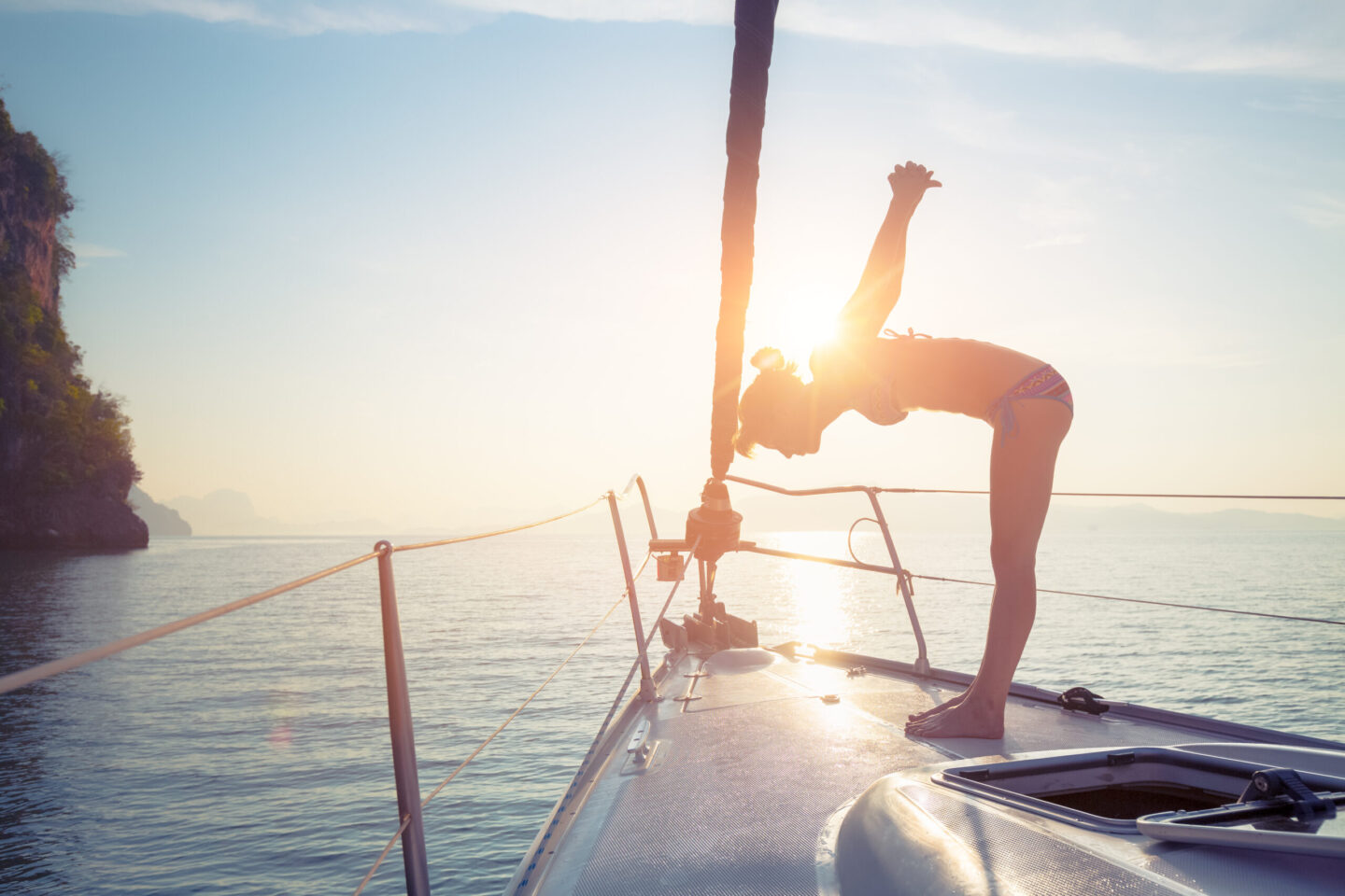 Wellness yacht charter woman doing yoga on bow at sunrise
