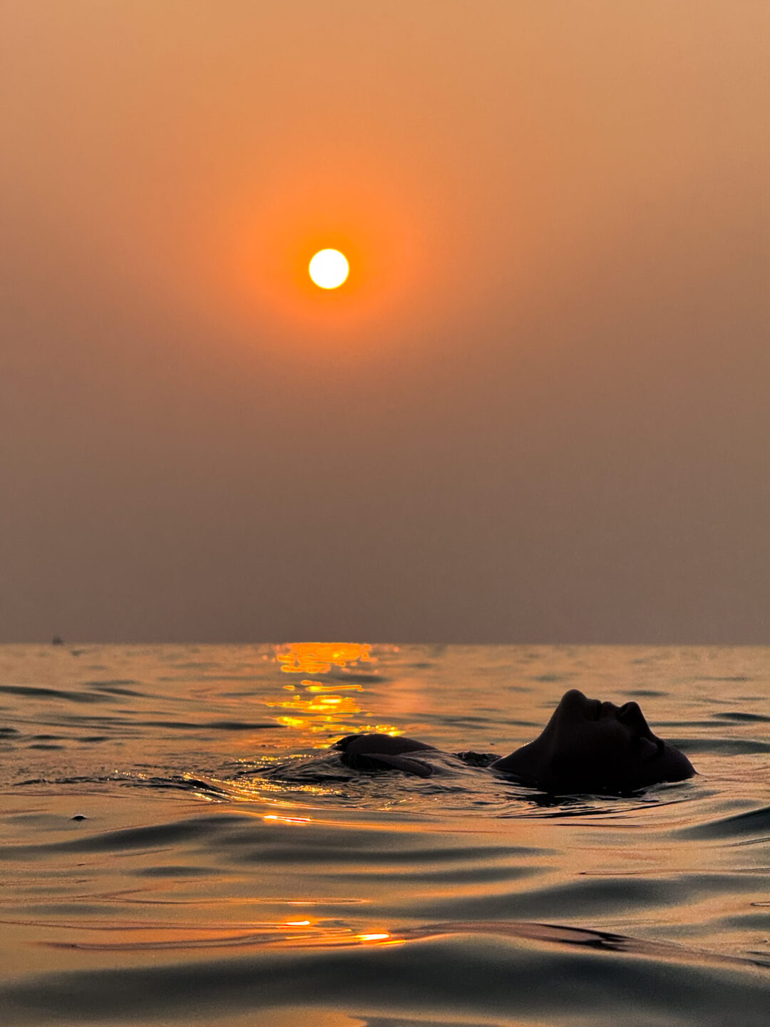 Gemma Fottles bathing in the Sunset in the ocean in Goa, India - best sunsets in the world