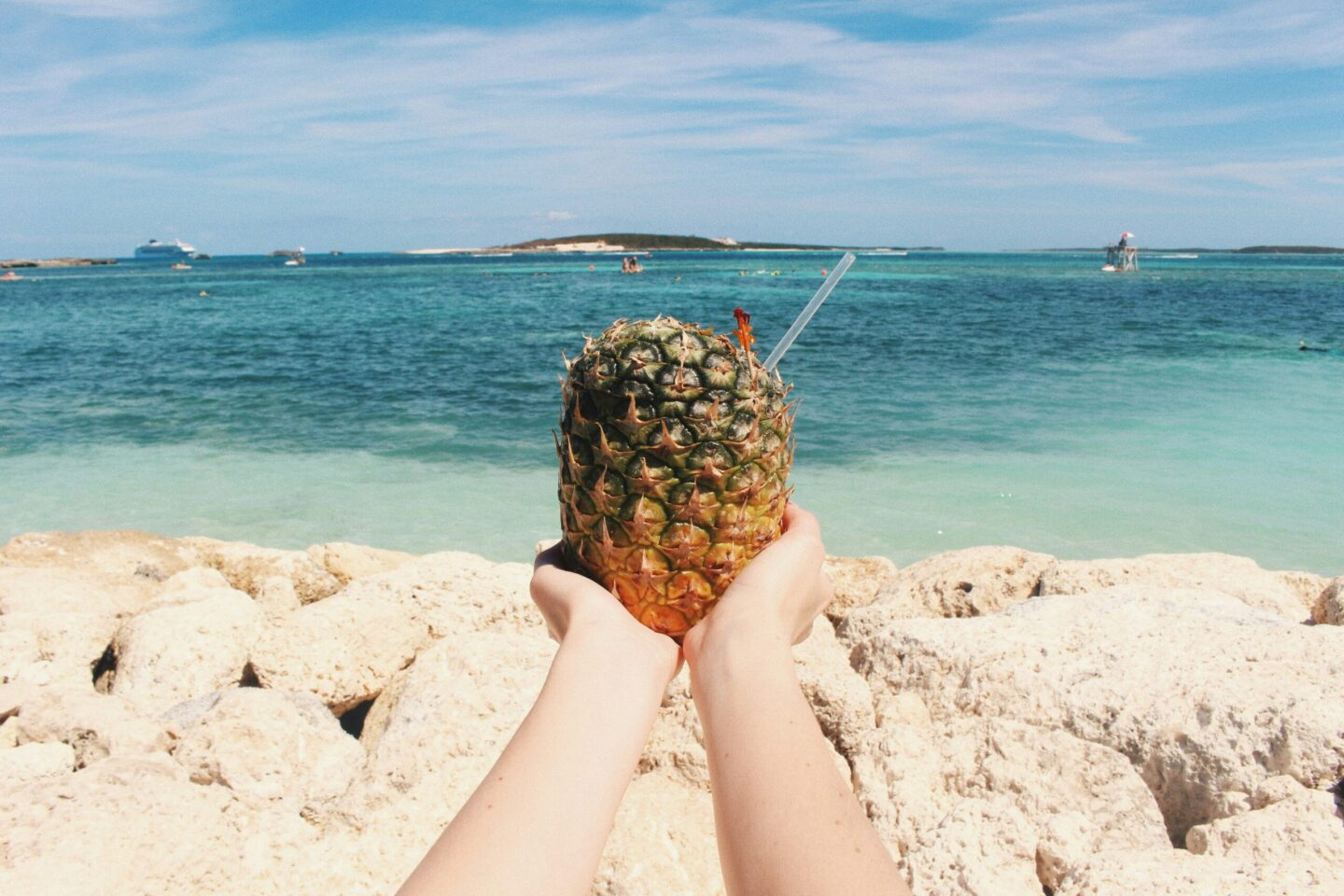 Pineapple drink in hands on Bahamas beach